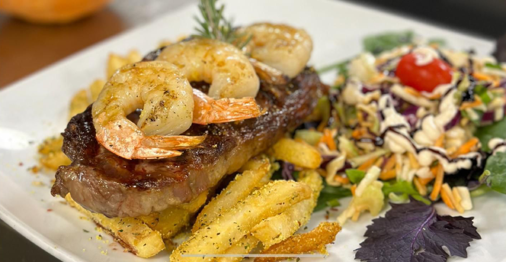 Steak with garlic prawns, chips and salad